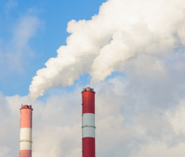 Zilās debesīs biezi balti dūmi no diviem kūpošiem skursteņiem