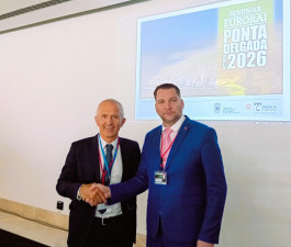 Divi formāli ģērbti vīrieši paspieduši rokas pozē kamerai